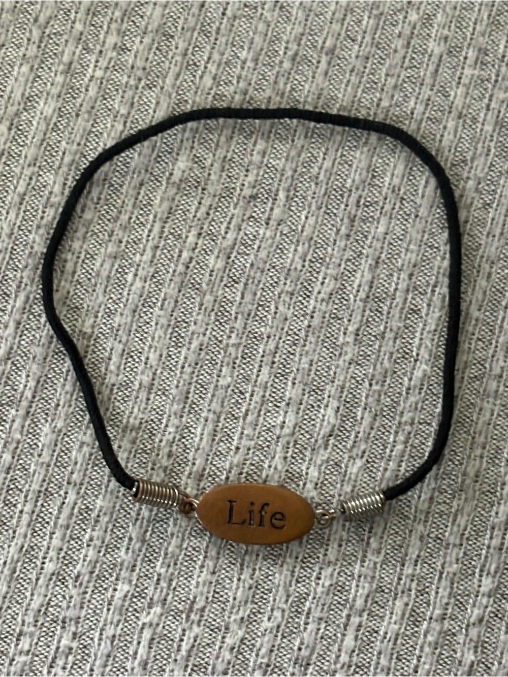 Black cord stretch bracelet w brown colored oval “Life” plaque